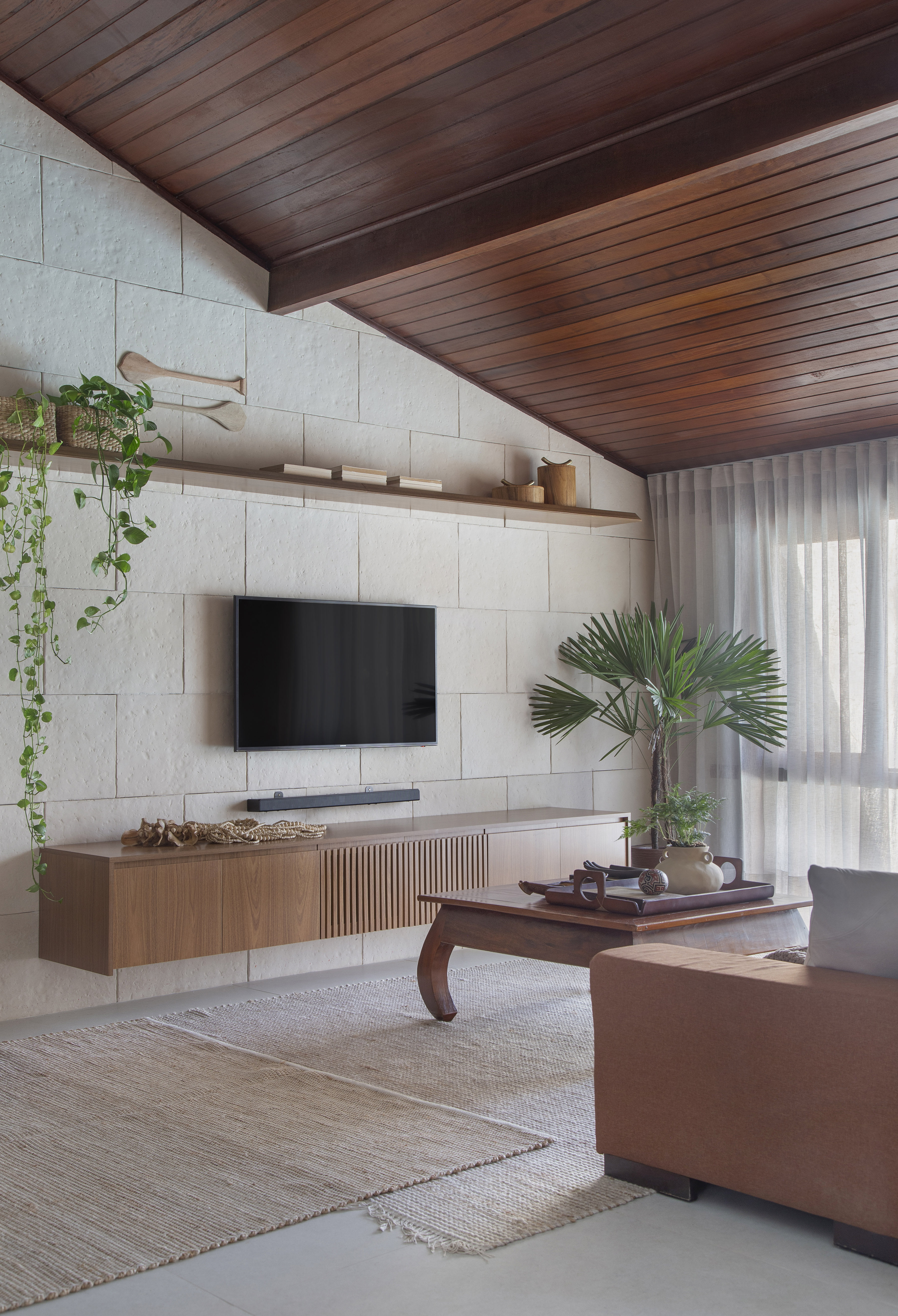 Ilha de cozinha revestida de azulejos com peixes é destaque nesta casa. Projeto de Travessa Arquitetura. Na foto, sala de estar, sala de tv, prateleira com plantas, palmeira.
