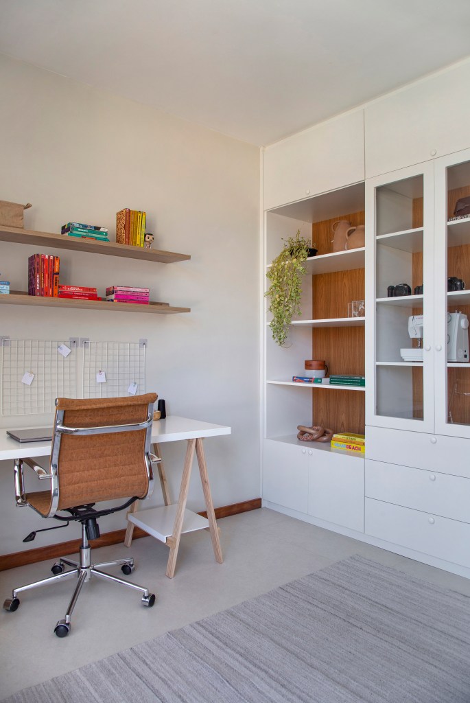 Ilha de cozinha revestida de azulejos com peixes é destaque nesta casa. Projeto de Travessa Arquitetura. Na foto, home office, mesa branca, prateleira, estante branca.