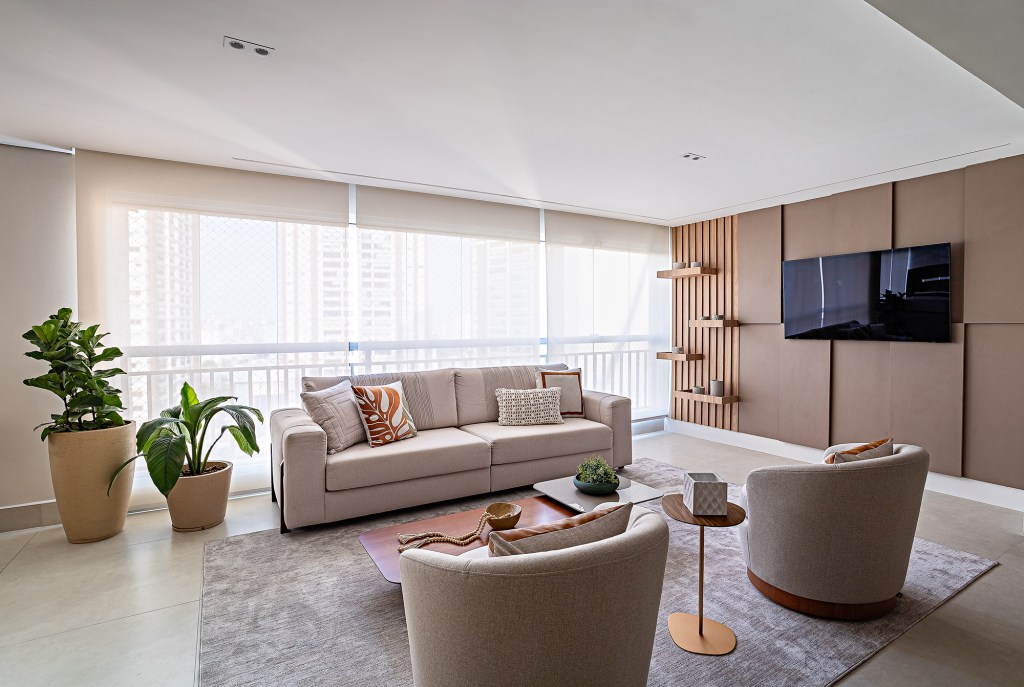 Iluminação natural, pedra e madeira marcam este apê de 225 m². Projeto de Juliana Ruba, Na foto, sala de estar com tv, sofá e jantar integrado.