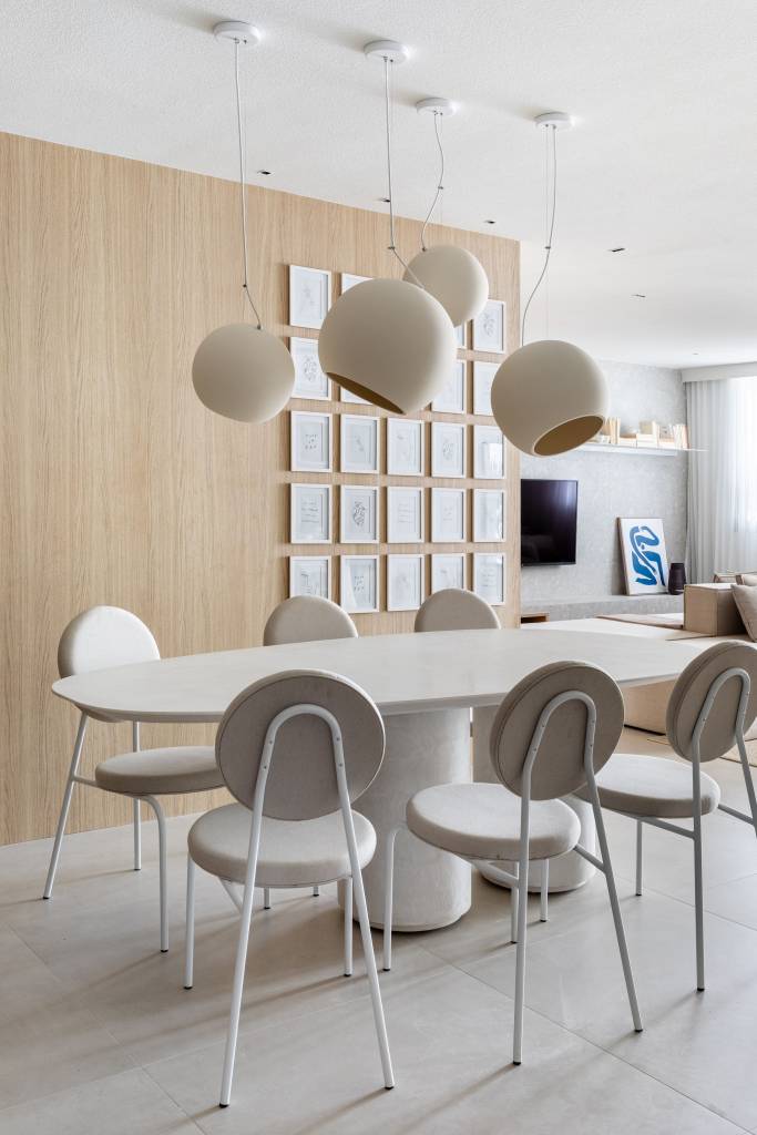 Japandi: apê de 110 m² tem décor delicado em tons de branco, rosa e cinza. Projeto de Up3 Arquitetura. Na foto, sala de jantar com mesa e cadeiras brancas, luminária branca. Quadros pequenos na parede.