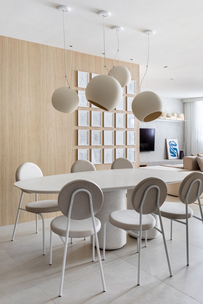 Japandi: apê de 110 m² tem décor delicado em tons de branco, rosa e cinza. Projeto de Up3 Arquitetura. Na foto, sala de jantar com mesa e cadeiras brancas, luminária branca. Quadros pequenos na parede.
