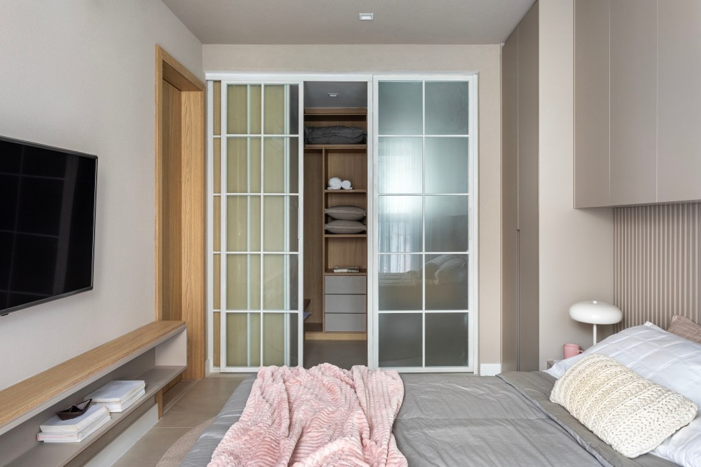 Japandi: apê de 110 m² tem décor delicado em tons de branco, rosa e cinza. Projeto de Up3 Arquitetura. Na foto, quarto com closet com porta de correr de vidro.
