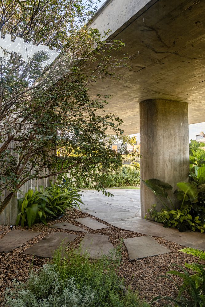 Jardins internos e externos interligam os cômodos desta casa de 500 m². Projeto de Stemmer Rodrigues. Na foto, pátio externo com jardim e pilares.