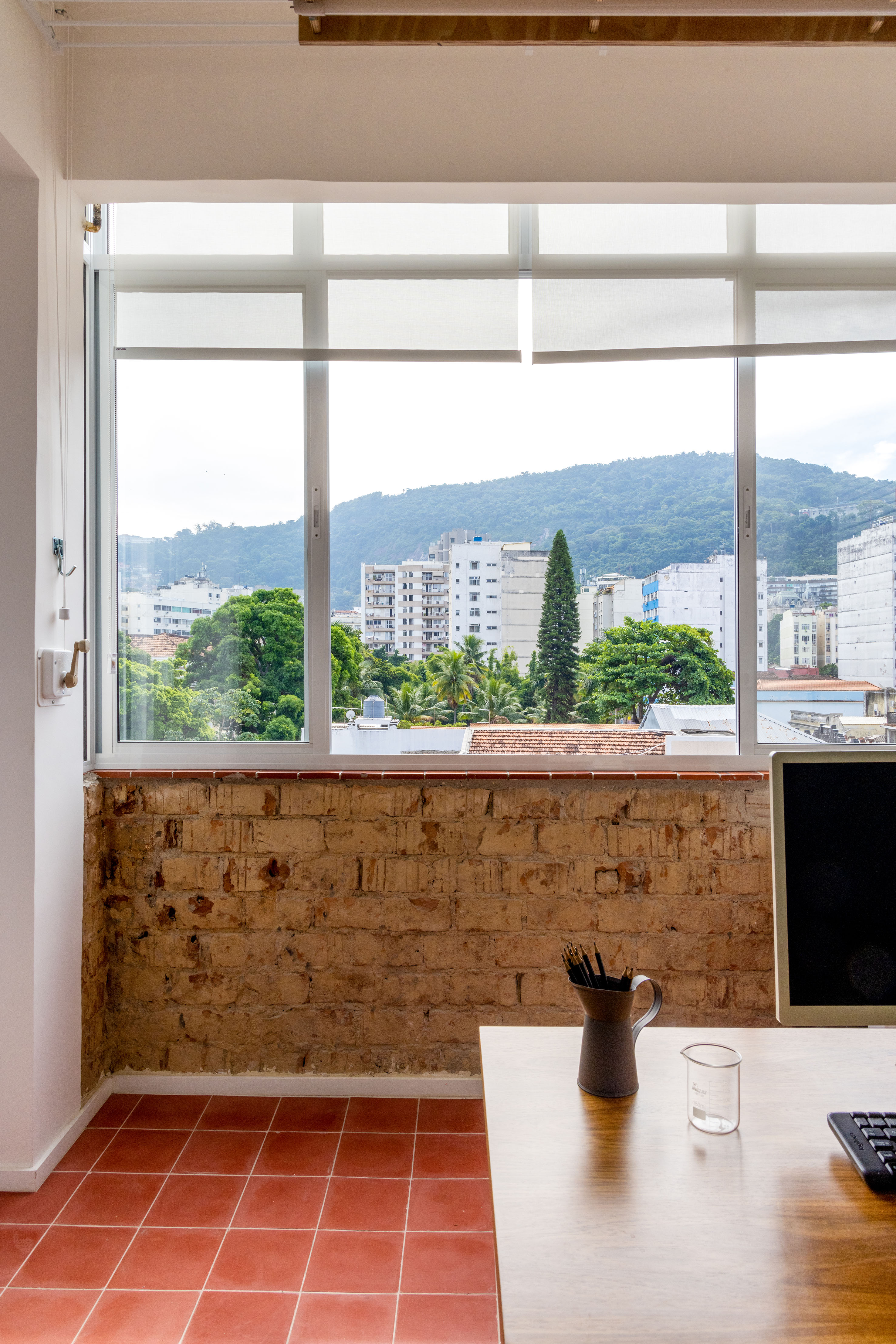 Ladrilhos hidráulicos trazem charme vintage e cor à apê de 90 m². Projeto de Ana Neri. Na foto, home office, janela, parede de tijolinhos.