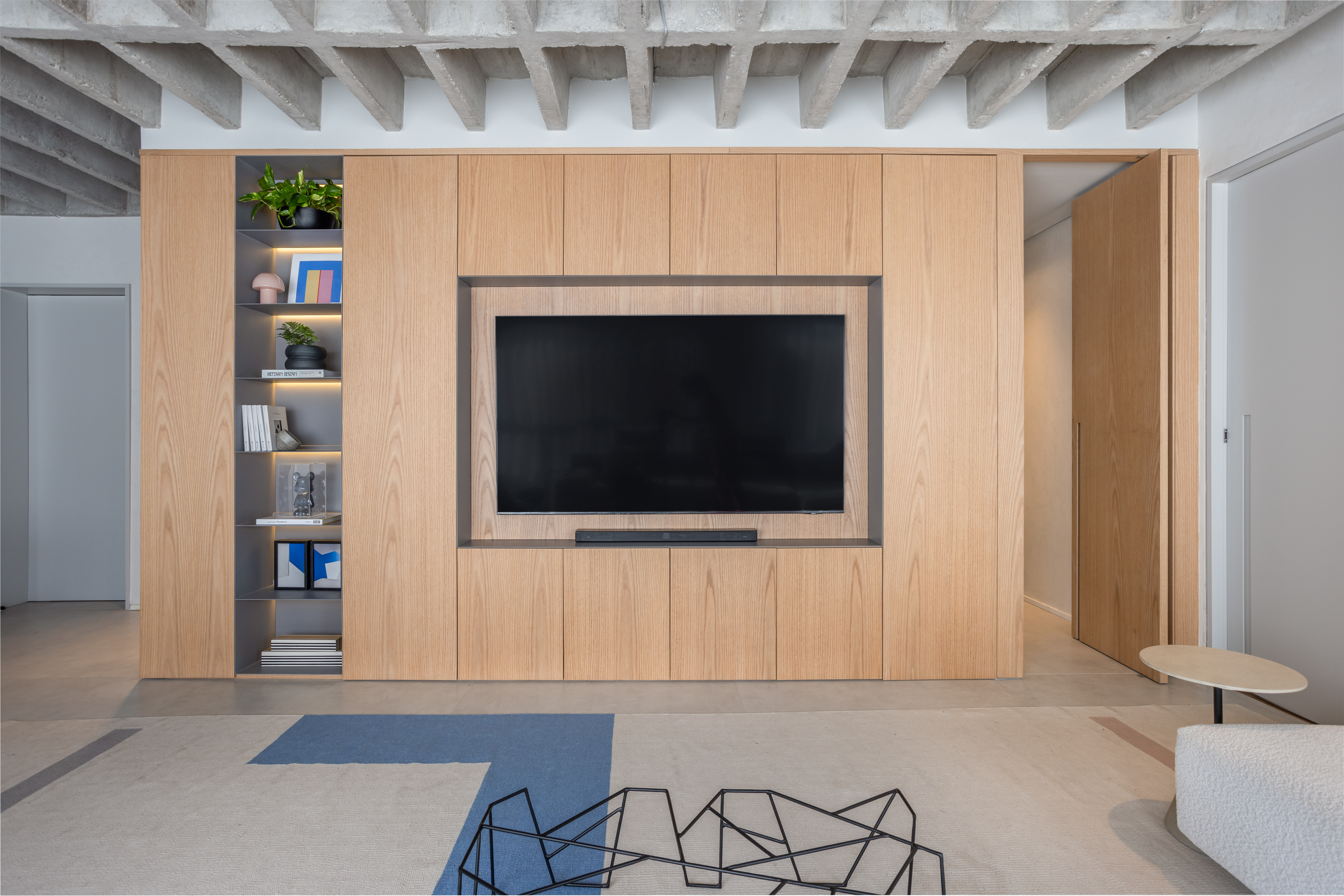 Laje de concreto, mesa em balanço e cozinha azul marcam apê de 115 m². Projeto do escritório Si Saccab. Na foto, marcenaria com porta camuflada.