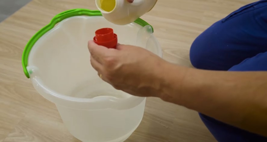 Posso lavar o piso vinílico? Veja como limpar o revestimento corretamente. Na foto, pessoa misturando detergente em balde com água.