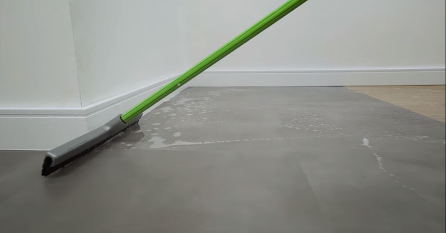 Posso lavar o piso vinílico? Veja como limpar o revestimento corretamente. Na foto, pessoa enxaguando piso vinílico