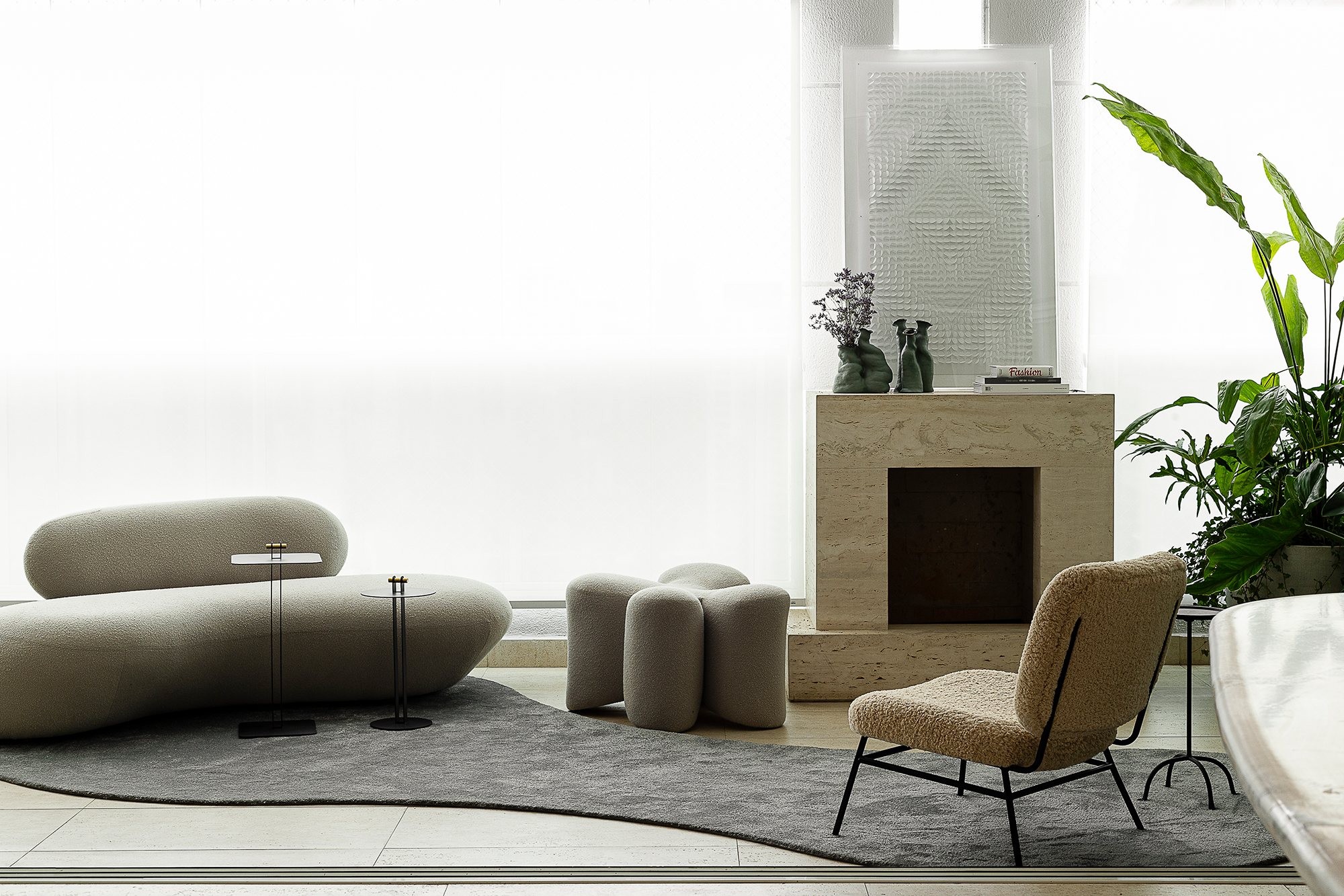 Linhas orgânicas e mobiliário solto compõem décor de apê alugado de 240 m². Projeto de Dubal Arquitetura. Na foto, sala com lareira, sofá e tapete.