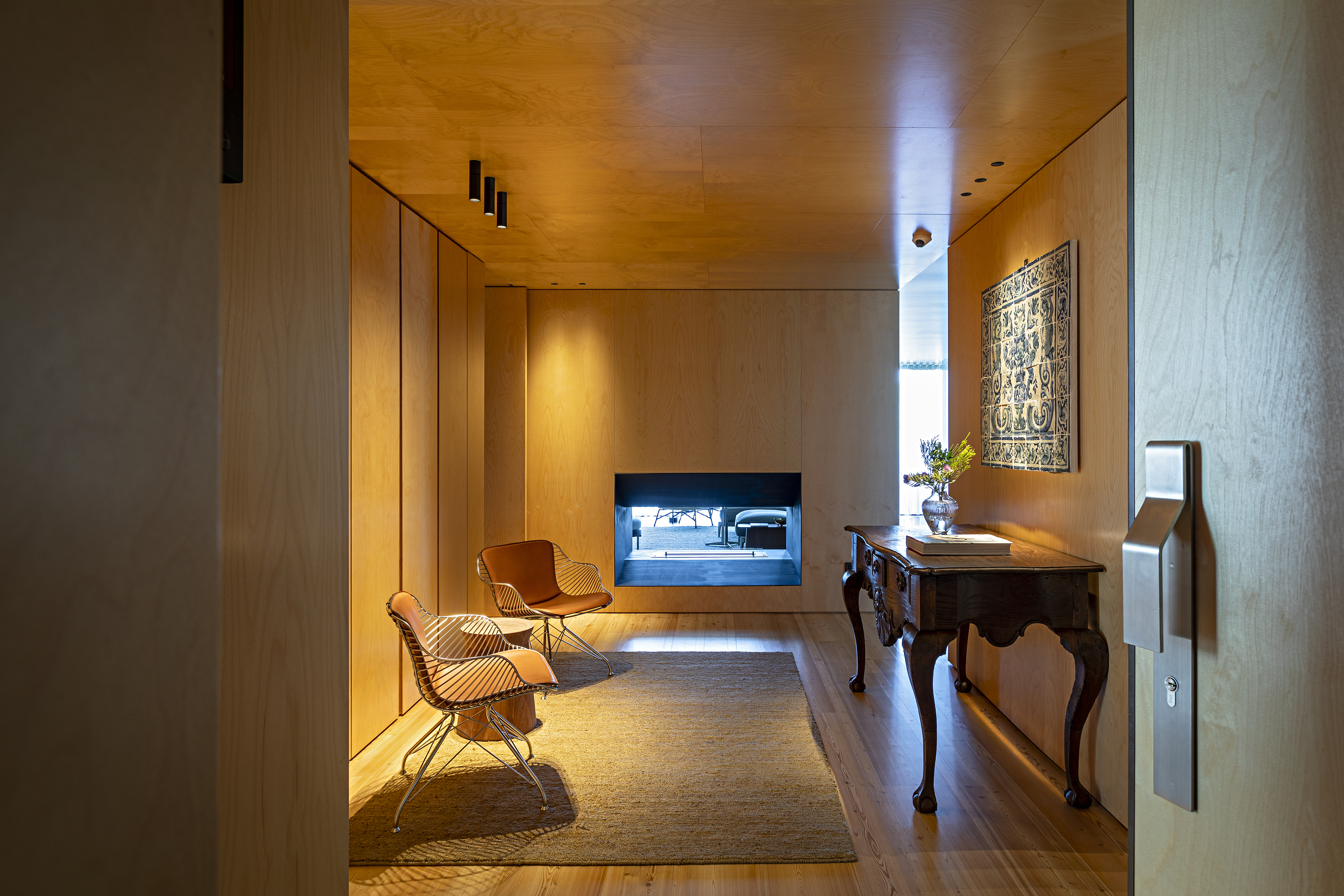 Mix entre antigo e moderno com diferentes cultuaras define apê de 290 m². Projeto de Andrea Chicharo Arquitetura. Na foto, sala revestida de madeira com poltronas e lareira.