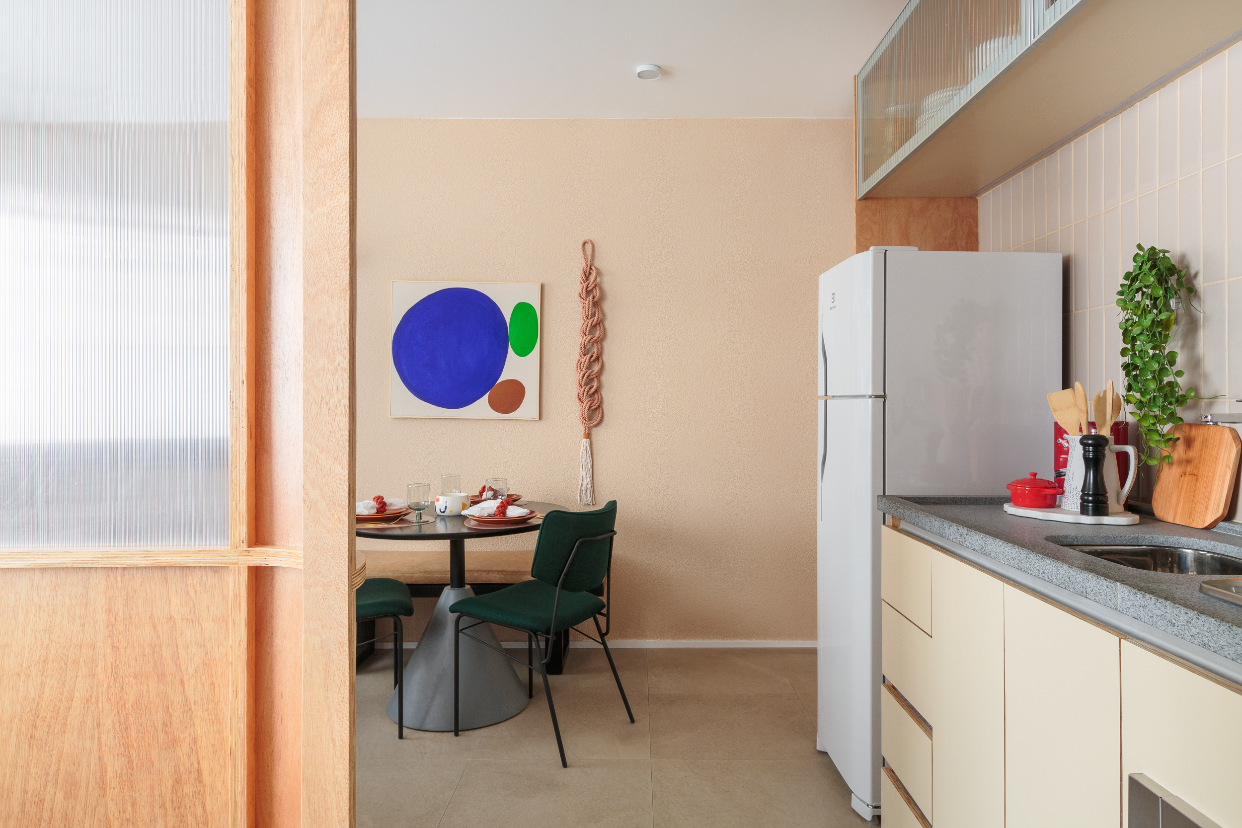 Painel translúcido e banco como rack otimizam o espaço em apê de 24 m². Projeto de Pro.a Arquitetos, Na foto, sala com sofá laranja e canto alemão,