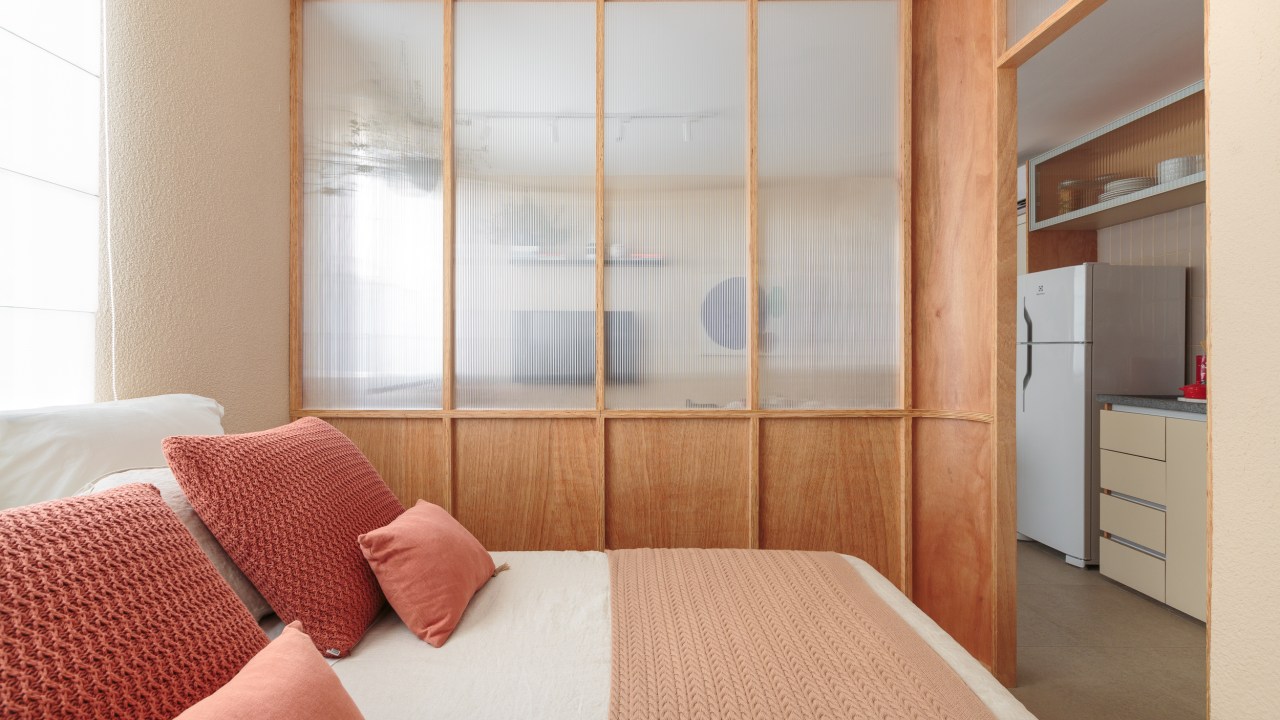 Painel translúcido e banco como rack otimizam o espaço em apê de 24 m². Projeto de Pro.a Arquitetos, Na foto, sala e quarto separados por um painel translúcido,
