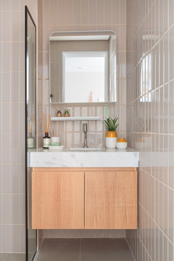 Painel translúcido e banco como rack otimizam o espaço em apê de 24 m². Projeto de Pro.a Arquitetos, Na foto, banheiro com espelho e tiles.