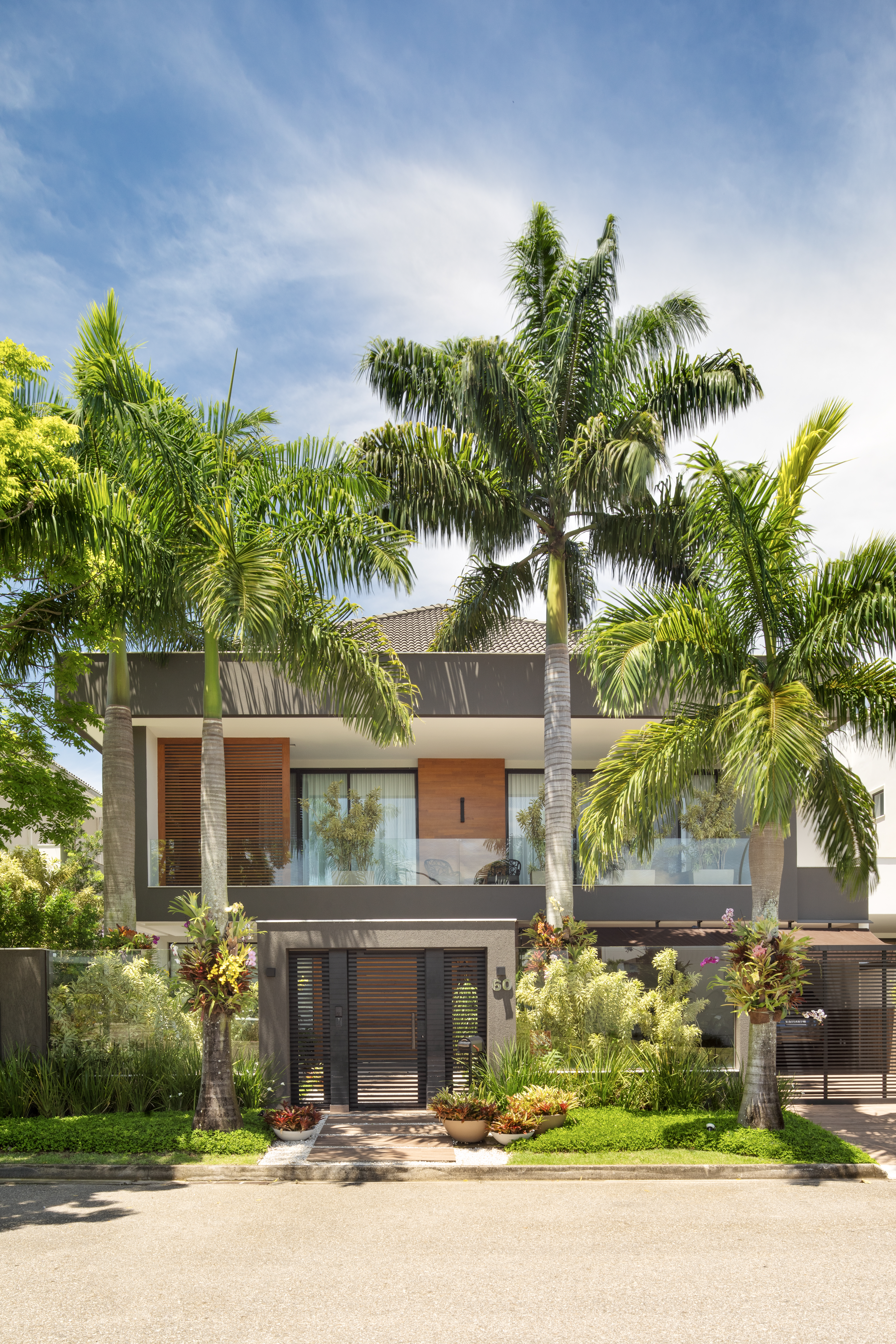 Paisagismo tropical: jardim tem bromélias, palmeiras e jardim vertical. Paisagismo de Horto Girassol. Na foto, fachada, casa, palmeiras.