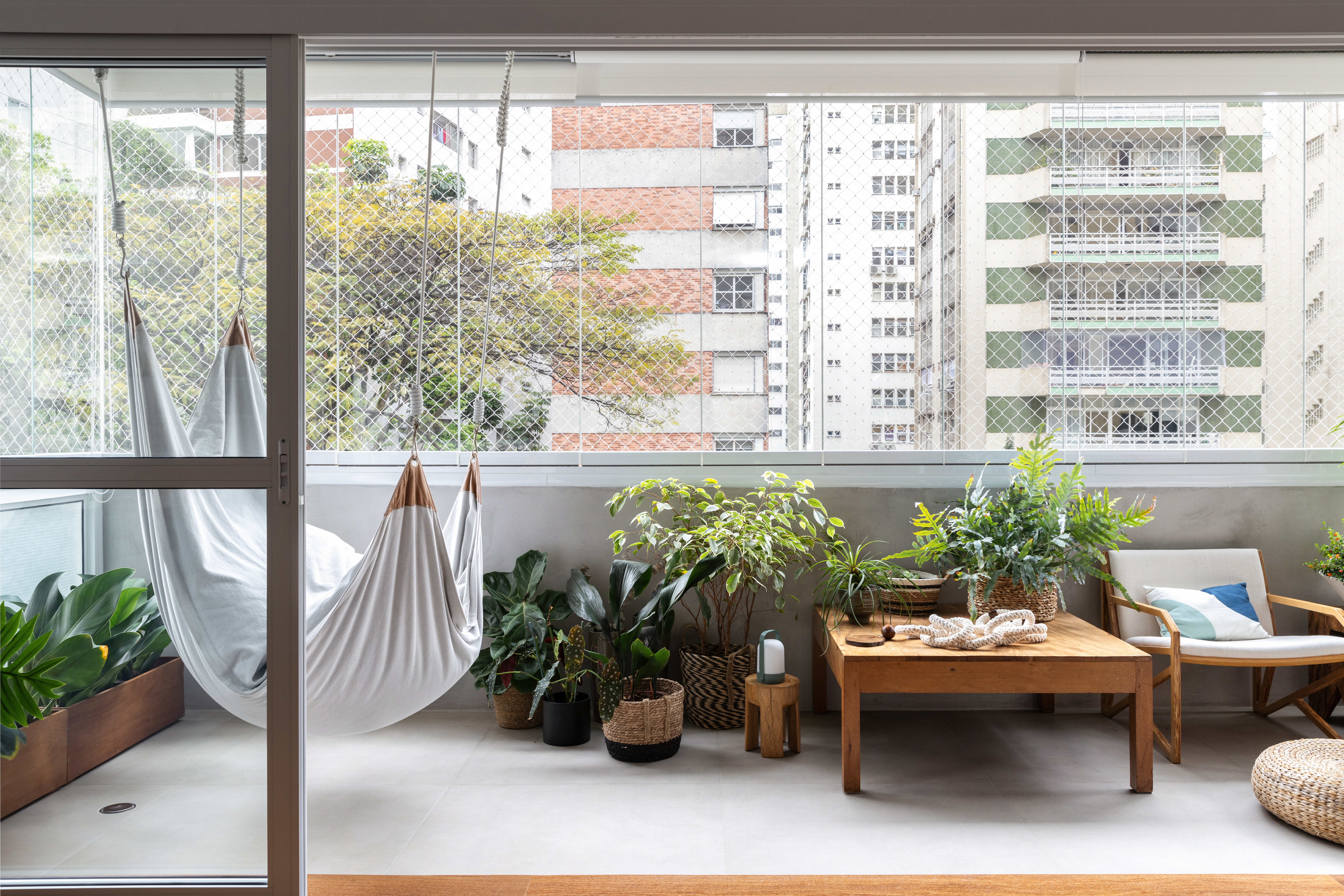Com paleta branca, apê de 240 m² tem porta de correr inspirada em biombos. Projeto de Lucia Manzano. Na foto, varanda, plantas, balanço.