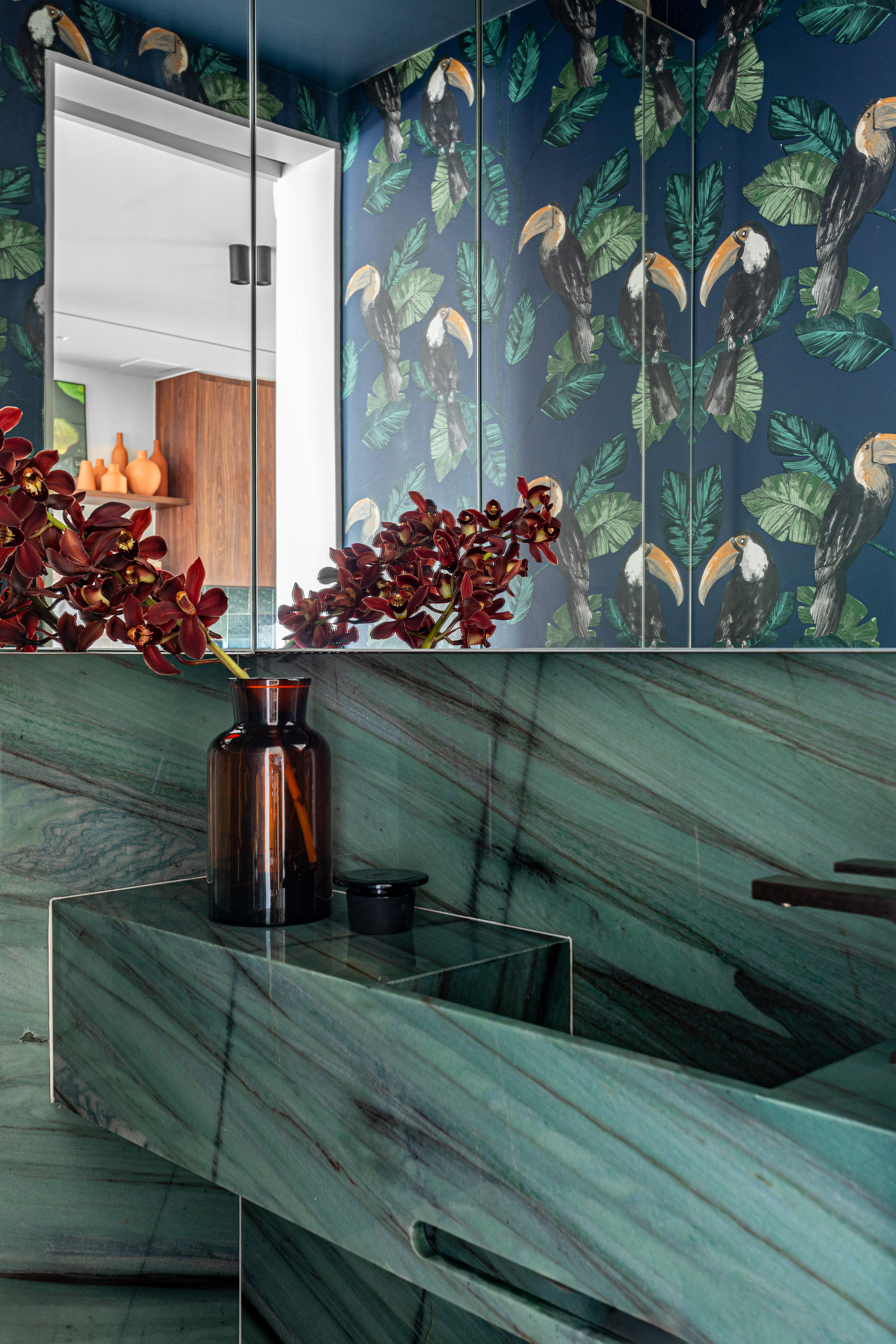 Peças afetivas com memória, design e madeira escura compõem apê de 116 m². Projeto de NOP Arquitetura. Na foto, lavabo com cuba esculpida, revestimento verde, papel de parede.