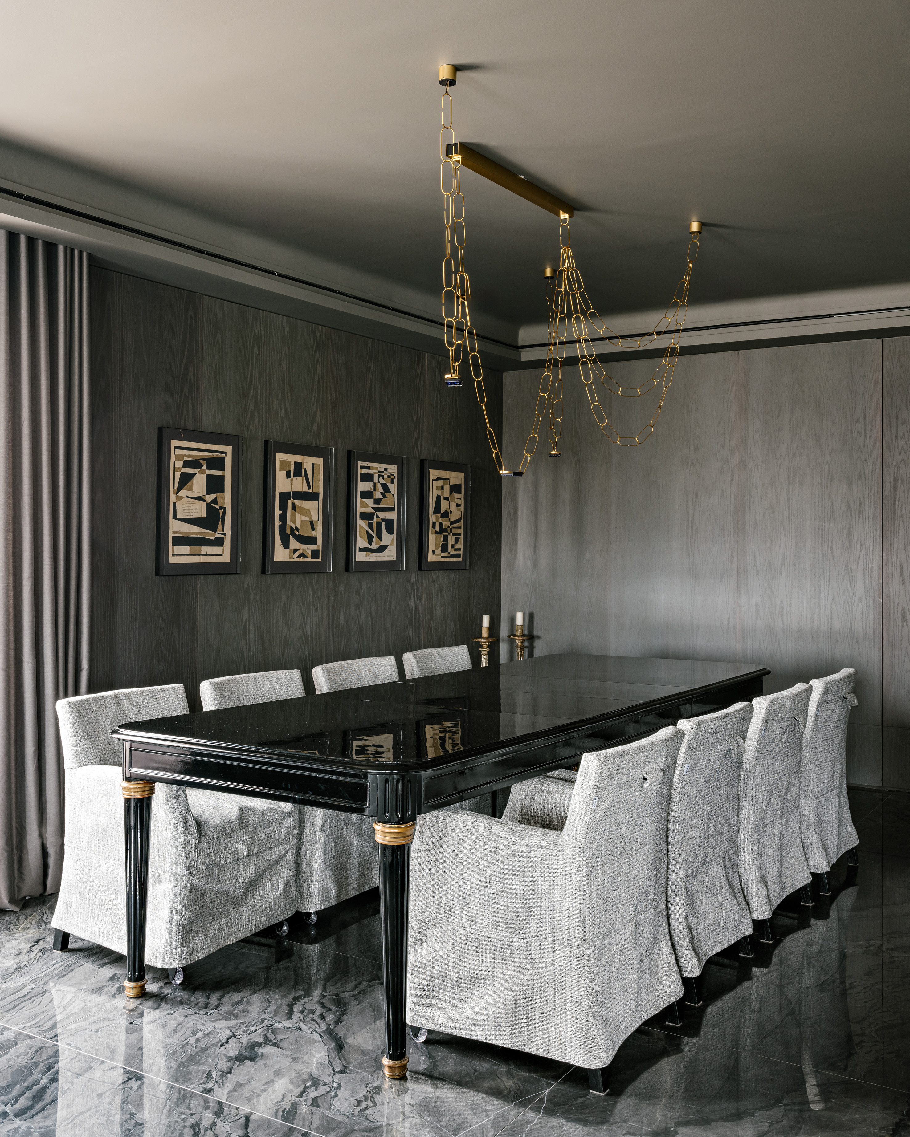 Piso de mármore e parede com painéis escuros dão elegância sóbria a apê. Projeto de DB Arquitetos. Na foto, sala de jantar, piso de mármore, mesa preta, cadeiras com capas brancas.