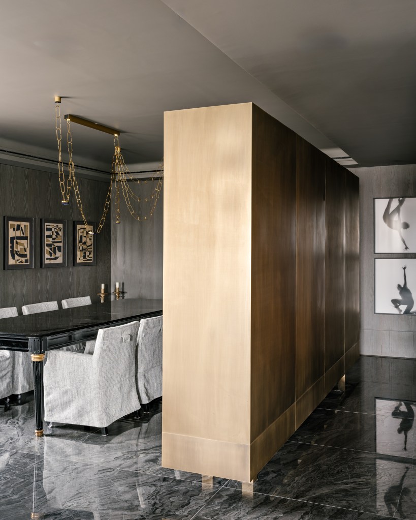 Piso de mármore e parede com painéis escuros dão elegância sóbria a apê. Projeto de DB Arquitetos. Na foto, sala de jantar, mesa preta, cadeiras com capas brancas.