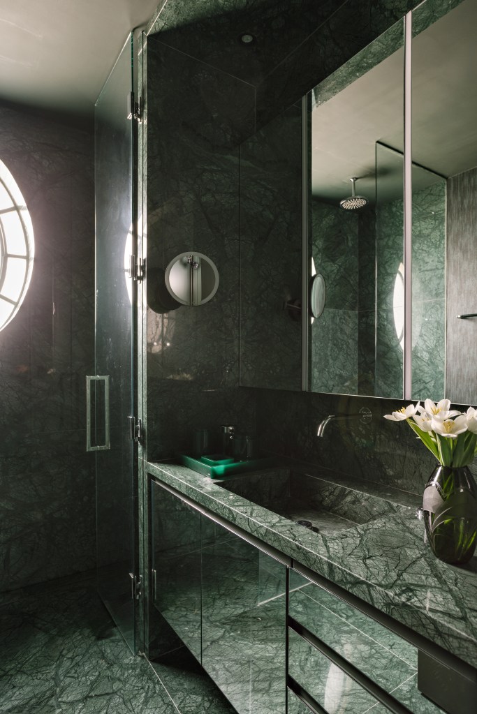 Piso de mármore e parede com painéis escuros dão elegância sóbria a apê. Projeto de DB Arquitetos. Na foto, banheiro com revestimento marmorizado verde escuro.