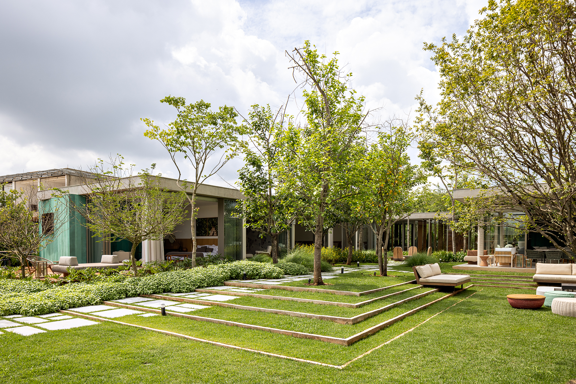 Placas de cobre oxidado e vidro integram esta casa de 653 m² à natureza, Projeto de FGMF. Na foto, fachada da casa com jardim.