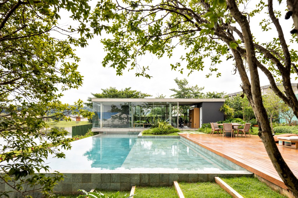 Placas de cobre oxidado e vidro integram esta casa de 653 m² à natureza, Projeto de FGMF. Na foto, fachada da casa com jardim e piscina.
