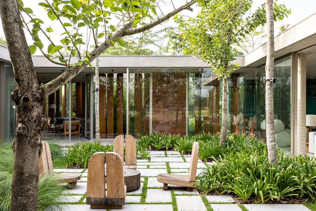 Placas de cobre oxidado e vidro integram esta casa de 653 m² à natureza, Projeto de FGMF. Na foto, fachada com brise e jardim.
