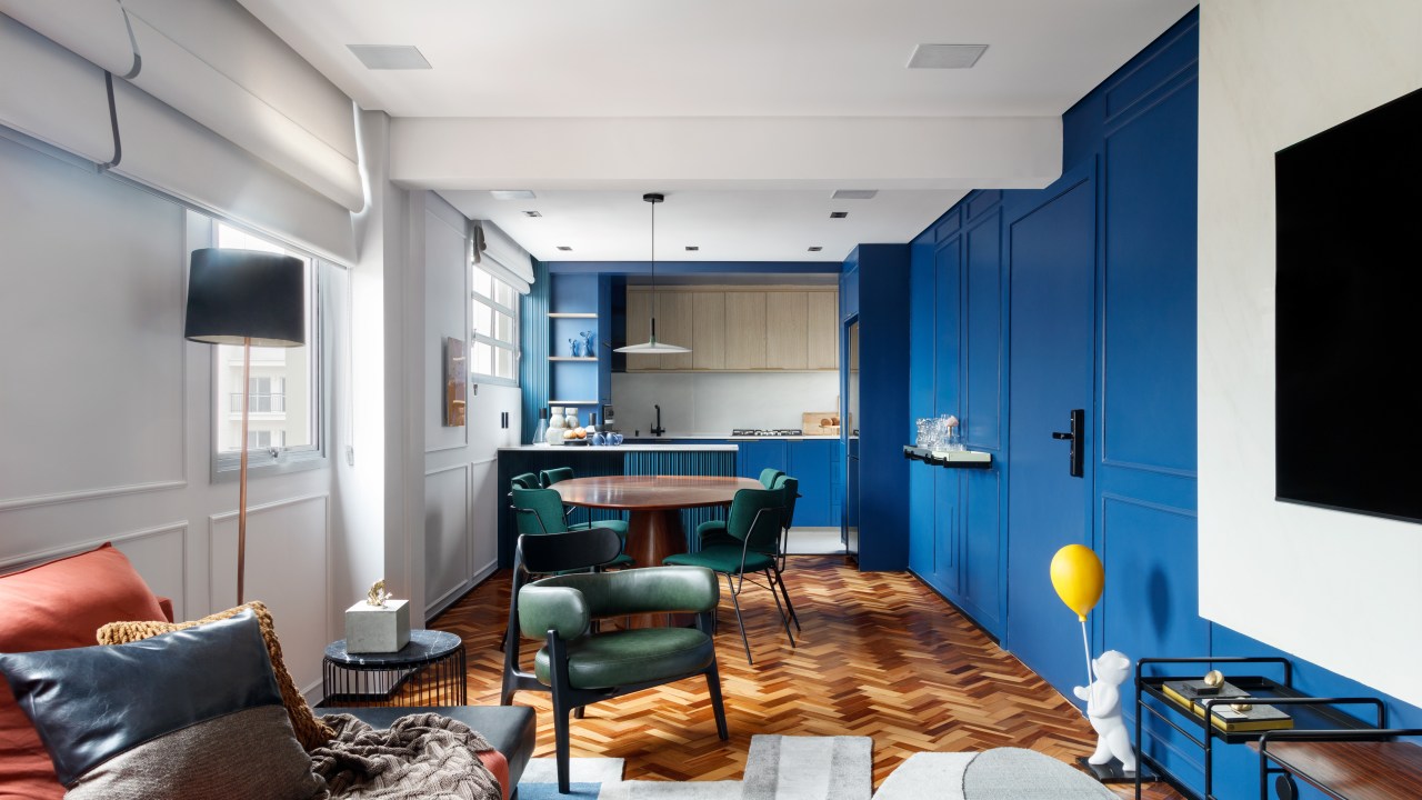 Rústico, retrô e contemporâneo: apê de 72 m² ganha vida com cozinha azul. Projeto de Ricardo Abreu. Na foto, sala com cozinha integrada, paredes de marcenaria azul e piso de espinha de peixe.