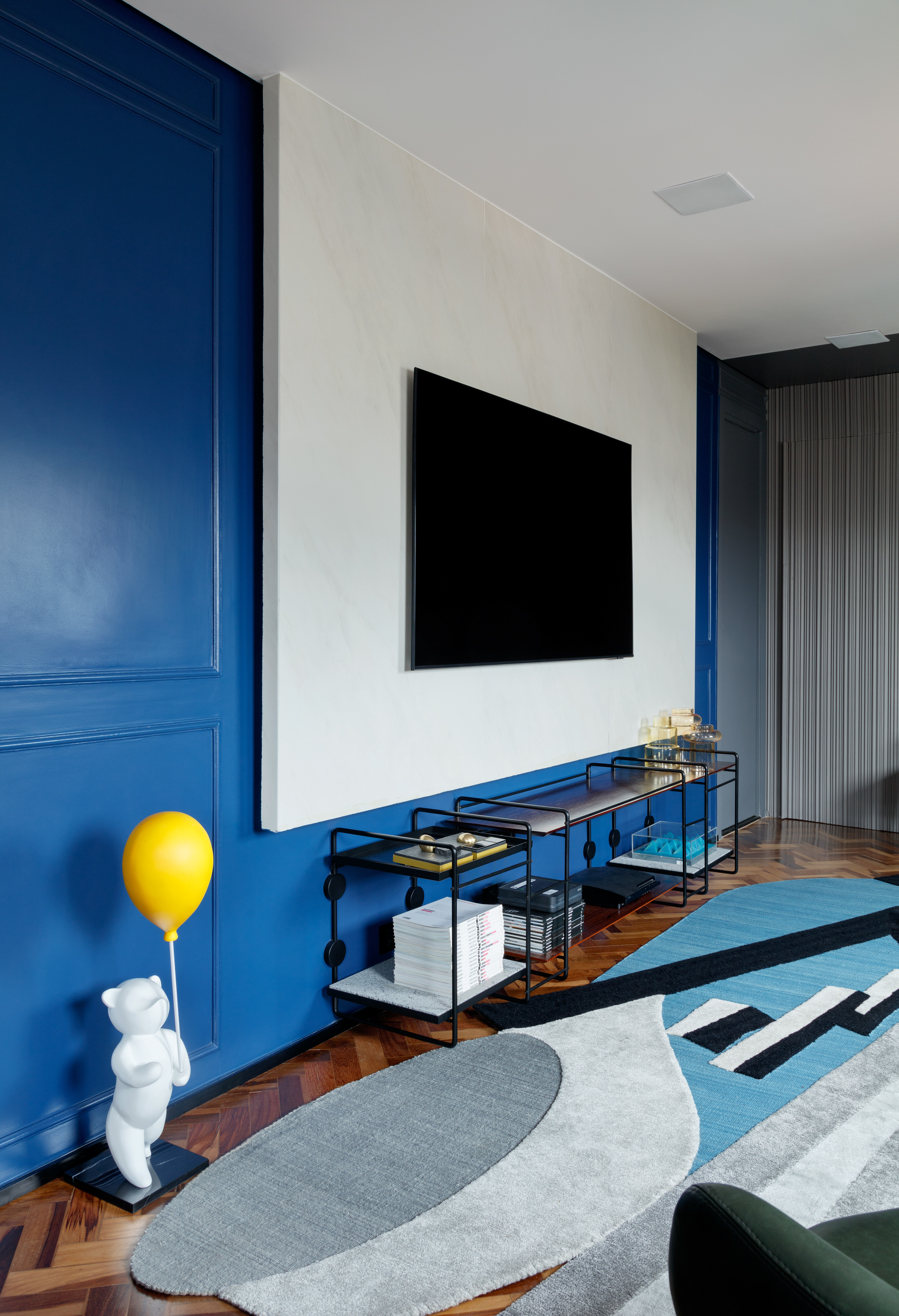 Rústico, retrô e contemporâneo: apê de 72 m² ganha vida com cozinha azul. Projeto de Ricardo Abreu. Na foto, sala com parede azul a painel de porcelanato.