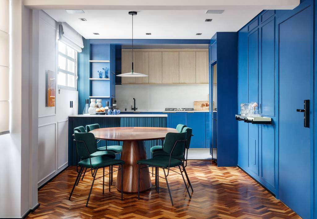 rustico-retro-contemporaneo-ape-72-m2-cozinha-azul-ricardo-abreu-credito-grutz (6) Rústico, retrô e contemporâneo: apê de 72 m² ganha vida com cozinha azul. Projeto de Ricardo Abreu. Na foto, sala com cozinha integrada, paredes de marcenaria azul e piso de espinha de peixe.