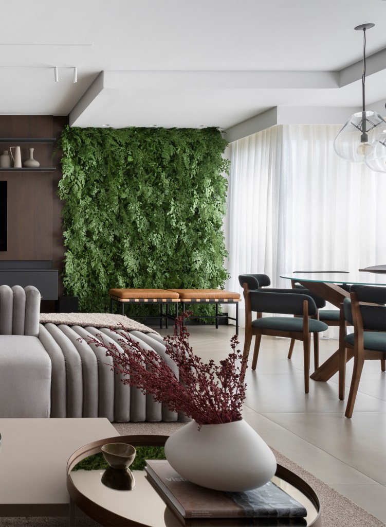 Sofá ilha é ponto central da sala de apê de 135m² com área gourmet. Projeto de Teto Arquitetura. Na foto, sala de estar com sofá ilha e jardim vertical.