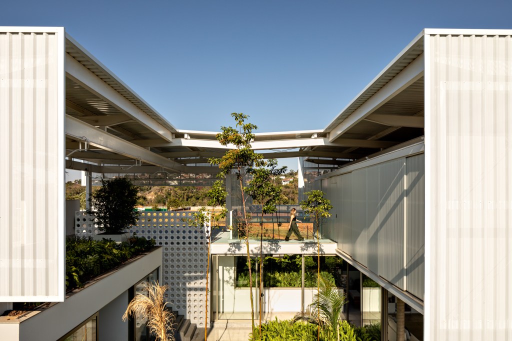 Treliças brancas de metal compõem a fachada desta casa em Campinas. Projeto de FGMF. Na foto, fachada com jardim.