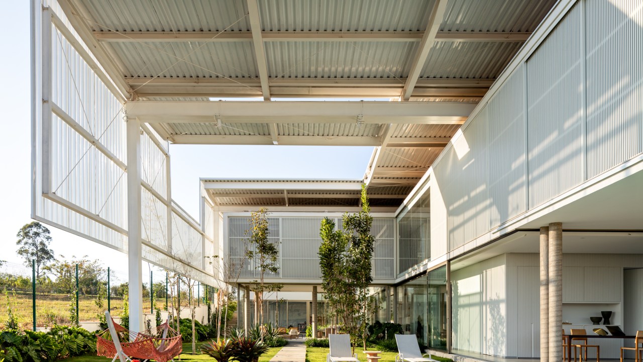 Treliças brancas de metal compõem a fachada desta casa em Campinas. Projeto de FGMF. Na foto, fachada com piscina e jardim.