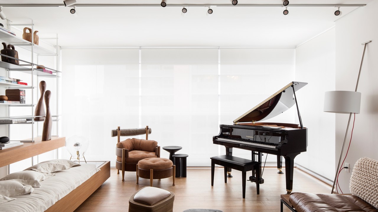 Apartamento de 150 m² une os hobbies do morador: piano, livros e filmes. Projeto de Nati Minas & Studio. Na foto, varanda com piano. sala de estar e jantar.