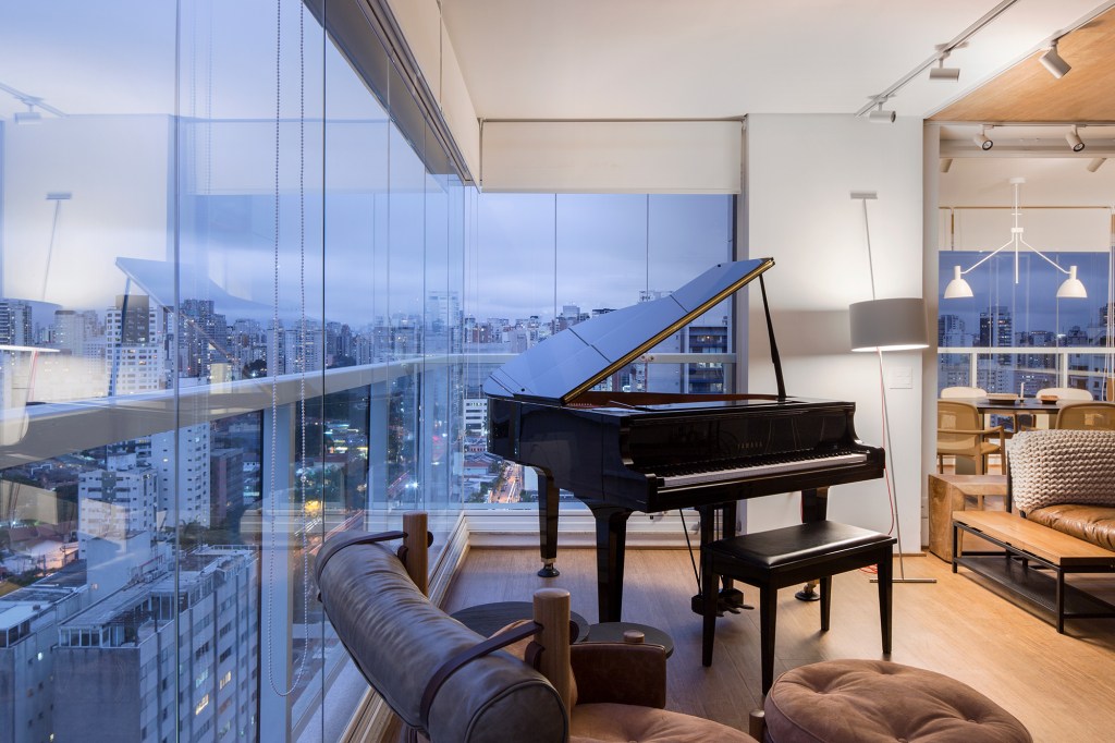 Apartamento de 150 m² une os hobbies do morador: piano, livros e filmes. Projeto de Nati Minas & Studio. Na foto, varanda com piano.