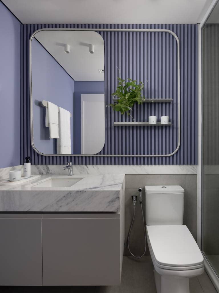 Apê de 142 m² tem paleta elegante de preto e branco e layout integrado. Projeto de Boher Arquitetos. Na foto, banheiro com parede roxa ripada e bancada marmorizada.