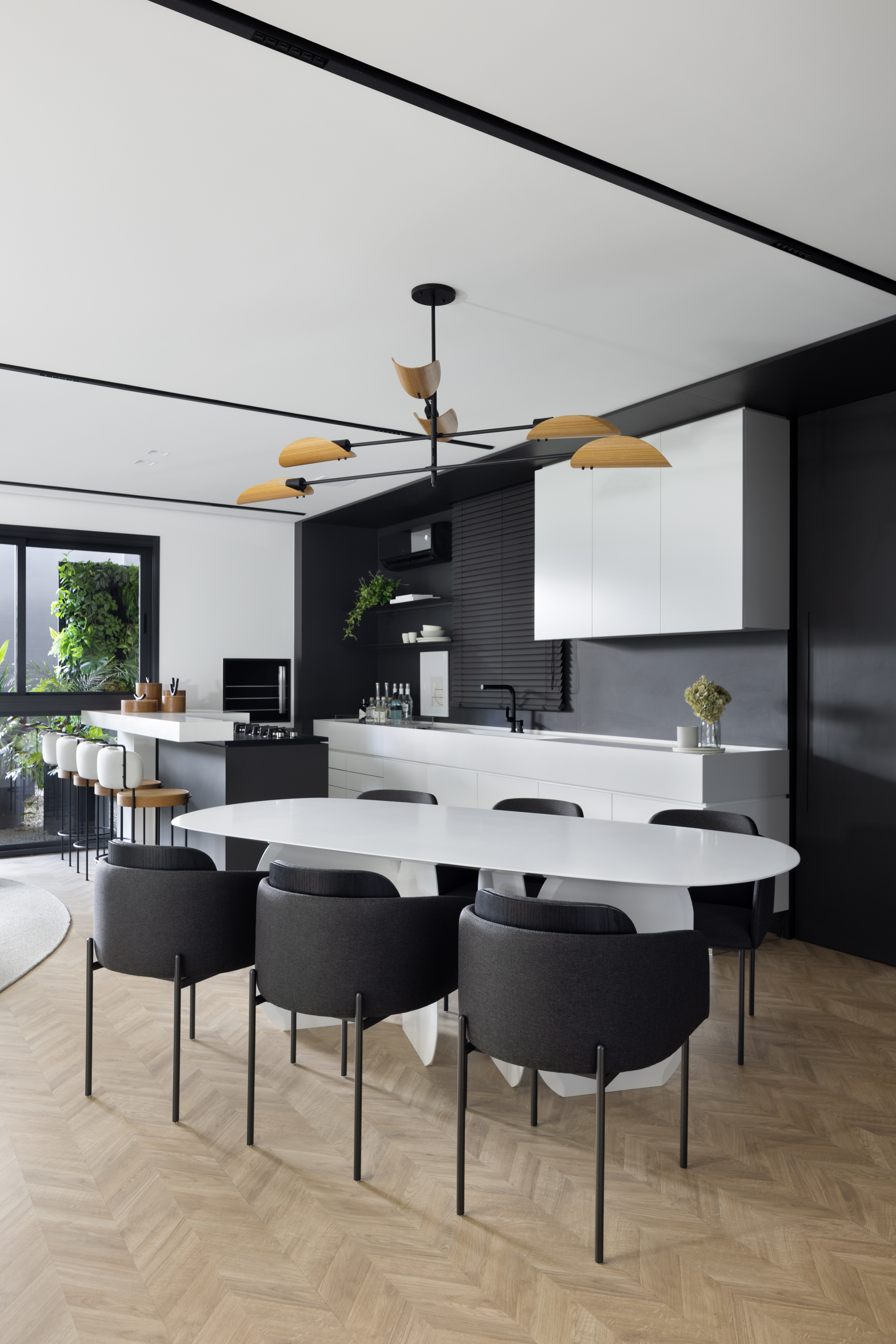 Apê de 142 m² tem paleta elegante de preto e branco e layout integrado. Projeto de Boher Arquitetos. Na foto, sala de jantar integrada com cozinha, mesa branca e cadeiras pretas.