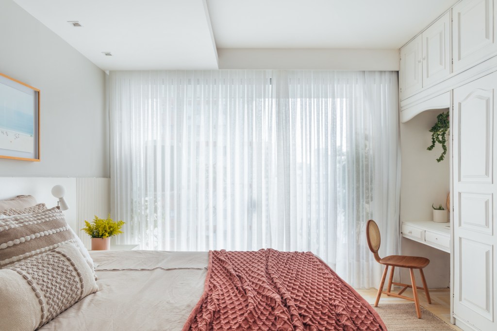 Apê de 160 m² em tons pastel alegres tem painel giratório de TV. Projeto de Ikeda Arquitetura. Na foto, quarto de casal, penteadeira, cortina branca.