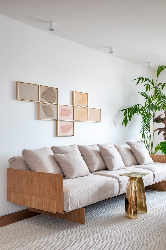Apê de 180 m² com sala íntima equilibra minimalismo e conforto. Projeto de Studio LAK. Na foto, sofá off white, quadros acima do sofá.