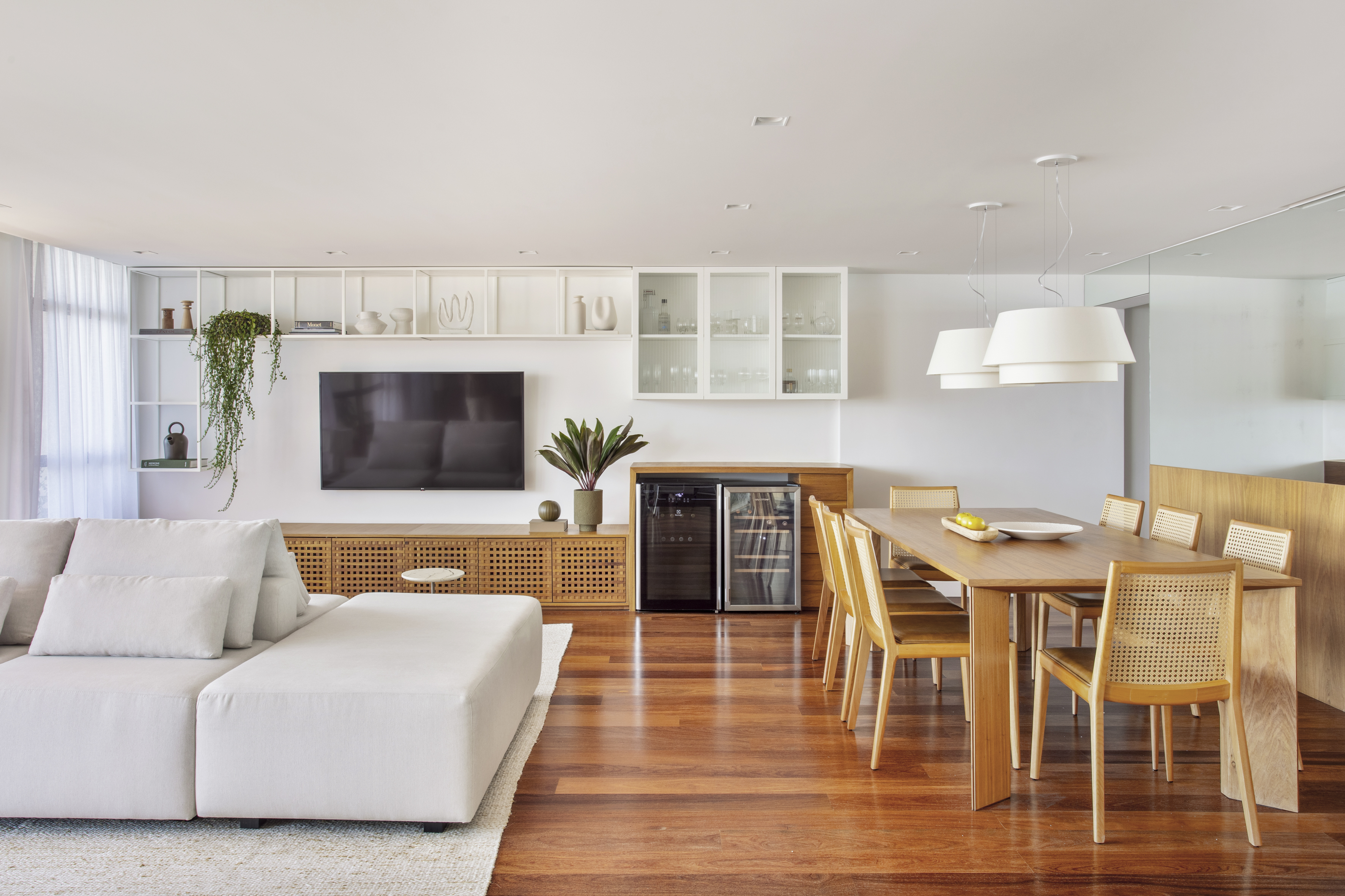 Apê de 300 m² tem sala íntima com TV e cozinha com armários amarelos. Projeto de PKB Arquitetura. Na foto, sala de estar integrada com sala de jantar, piso de madeira.