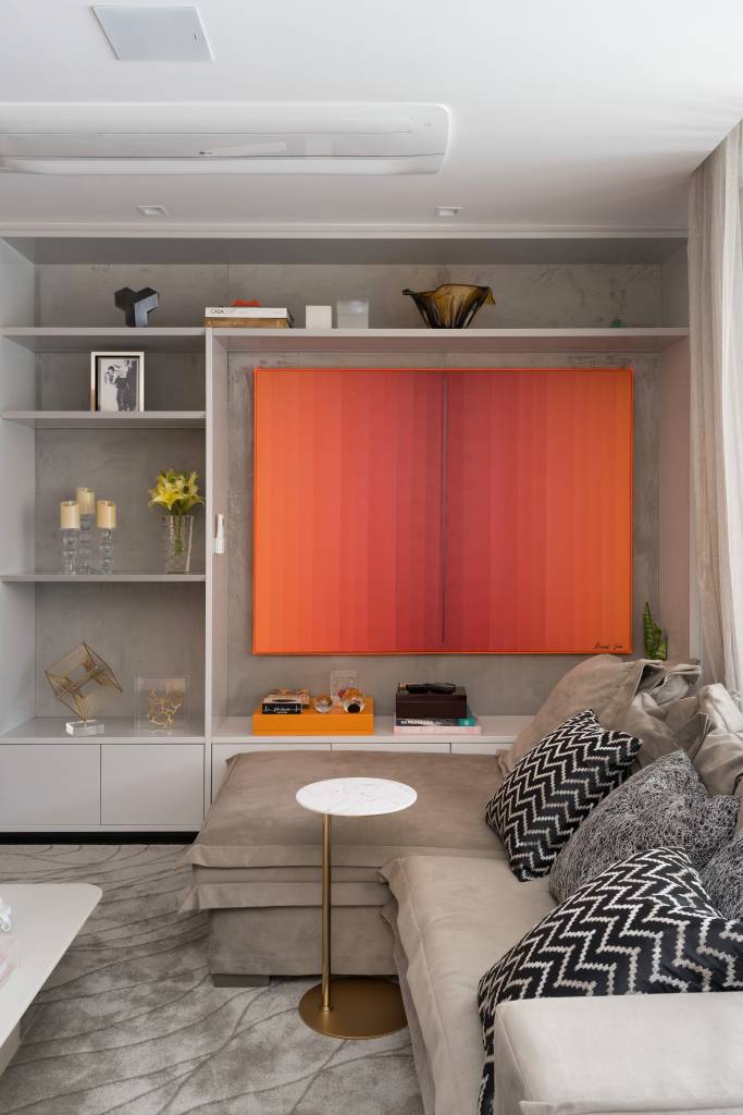 Apê ganha closet walk-in, cozinha verde oliva e banheiro com cromoterapia. Projeto de Spaço Interior. Na foto, sala de estar, quadro vermelho, estante com nichos, sofá bege.