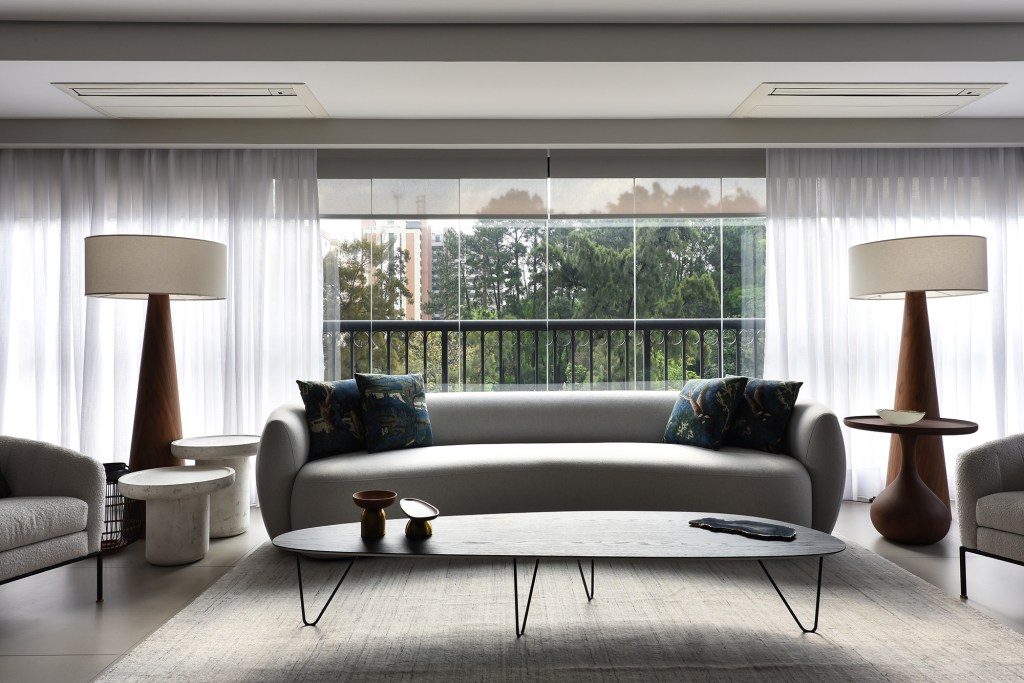 Apê industrial de 360 m² é inspirado nos lofts de Nova York. Projeto de Rebeca Catalucci. Na foto, varanda com sofá curvo e abajures.