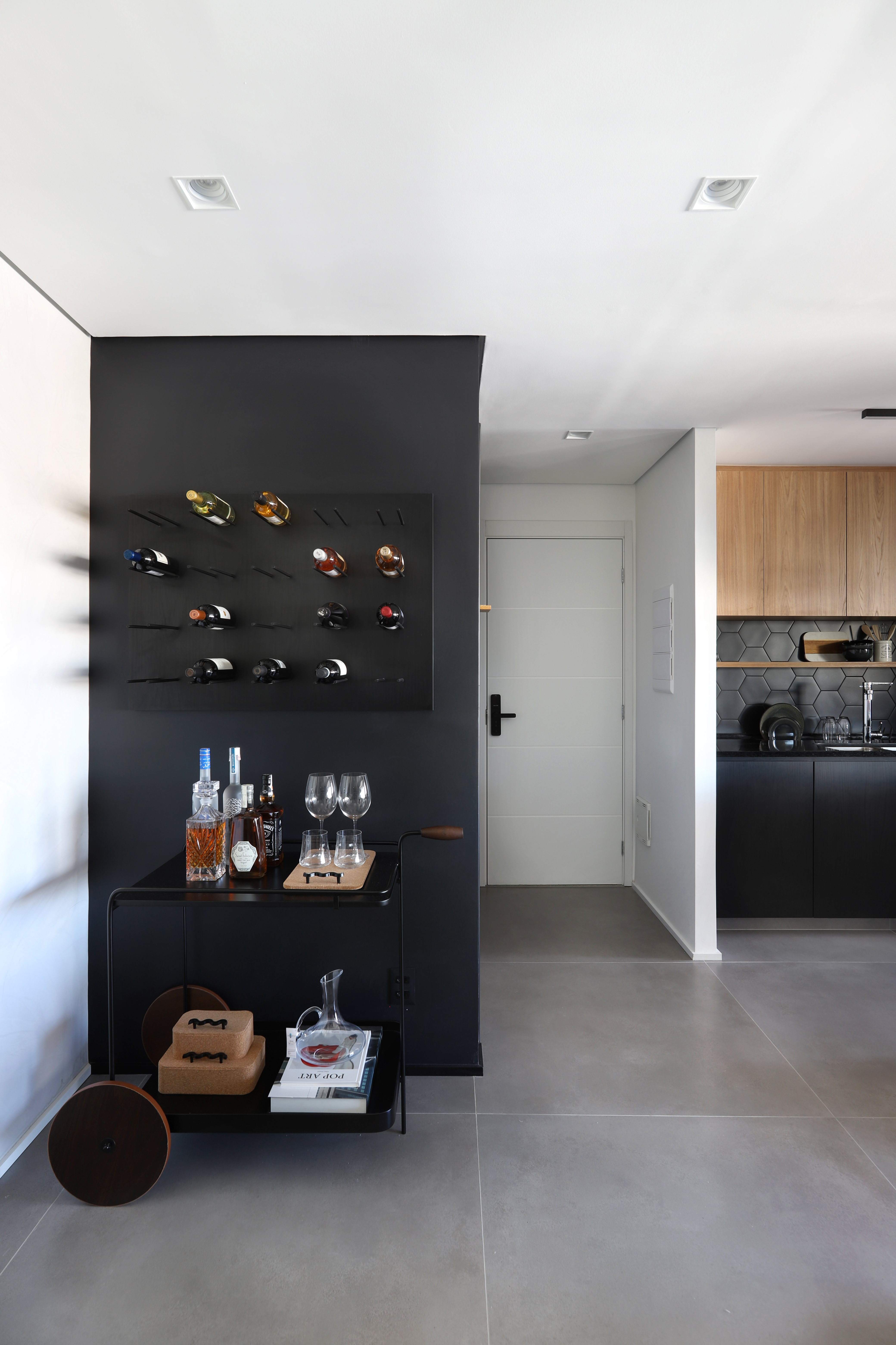 Apê em tons de preto de 91 m² tem cantinho de degustação de vinho. Projeto de Fantato Nitoli Arquitetura. Na foto, cantinho de bar com adega.