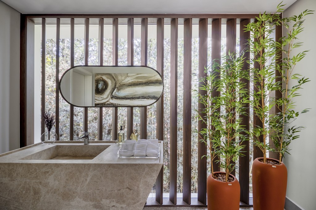 Área gourmet integrada ao jardim é o coração desta casa. Projeto de TM Arquitetura. Na foto, lavabo com parede com brises e cuba esculpida.