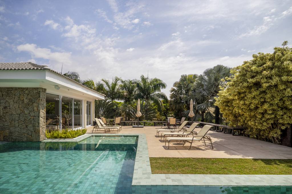 Área gourmet integrada ao jardim é o coração desta casa. Projeto de TM Arquitetura. Na foto, piscina com jardim e varanda.