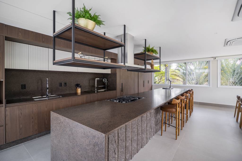 Área gourmet integrada ao jardim é o coração desta casa. Projeto de TM Arquitetura. Na foto, varanda gourmet com ilha, jantar e estar.