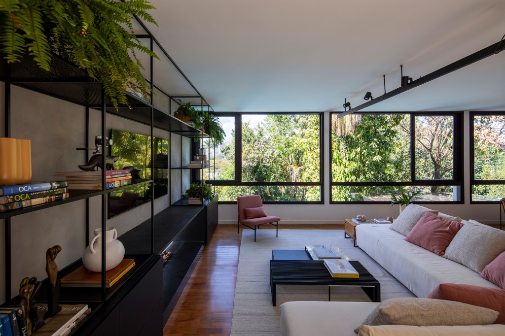 Casa dos anos 1950 ganha novo projeto que preserva a arquitetura original, Projeto de Conrado Ceravolo. Na foto, sala de estar e tv com lareira e sofás.