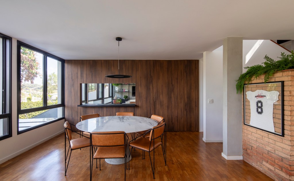 Casa dos anos 1950 ganha novo projeto que preserva a arquitetura original, Projeto de Conrado Ceravolo. Na foto, sala de jantar com mesa redonda e vista para o jardim.