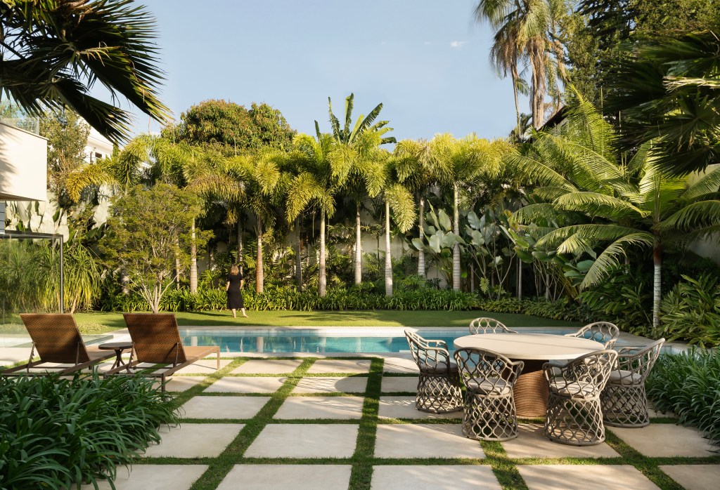Casa integrada ao jardim e tem painel de azulejos de Alexandre Mancini. Projeto de Rogério da Fonseca. Na foto, jardim com palmeiras, folhagens e piscina.