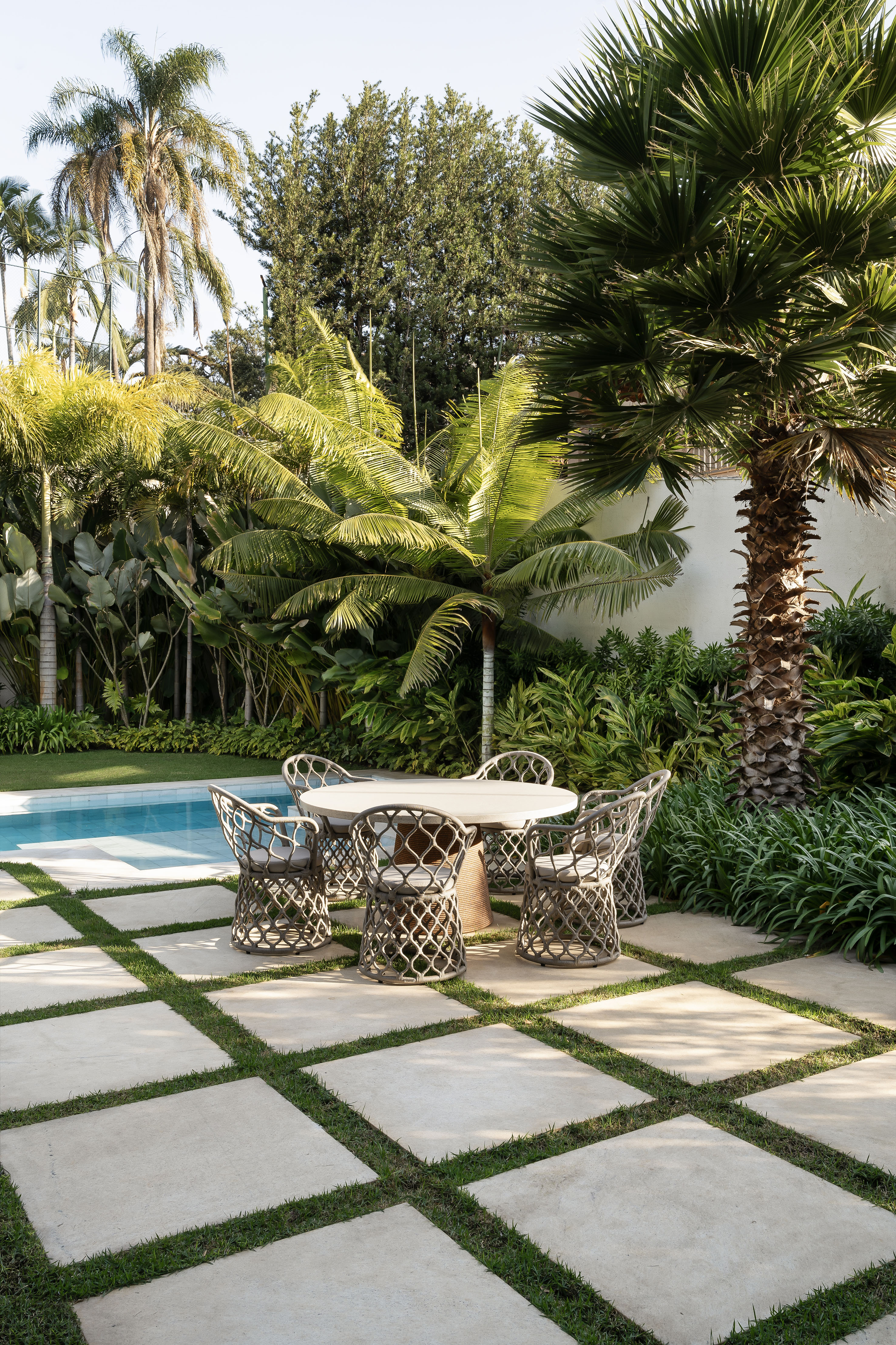 Casa integrada ao jardim e tem painel de azulejos de Alexandre Mancini. Projeto de Rogério da Fonseca. Na foto, jardim com palmeiras, folhagens e piscina.