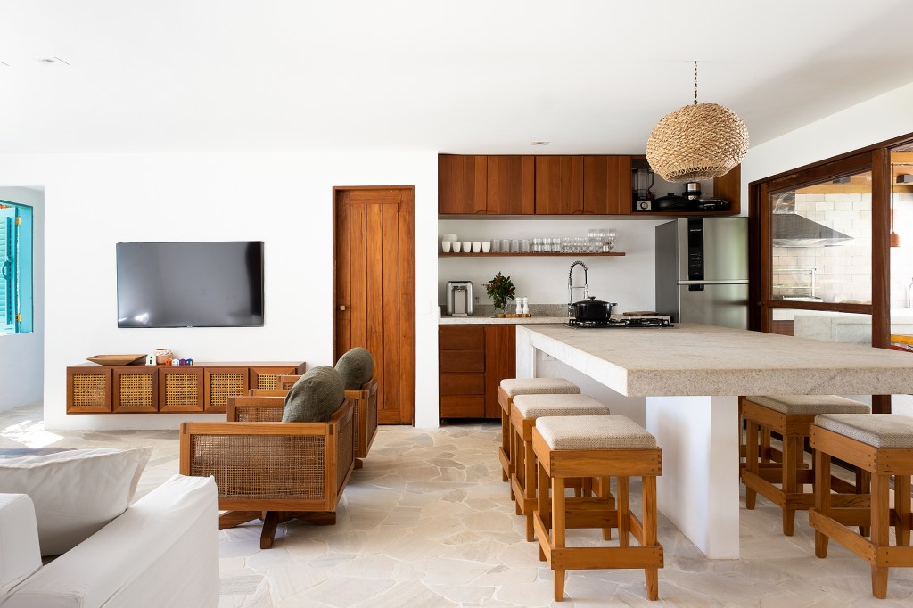 Casa em Trancoso integrada à natureza tem quartos de hóspedes na edícula. Projeto de Conrado Ceravolo. Na foto, sala de estar, cozinha e jantar integrados, Móveis de palhinha.