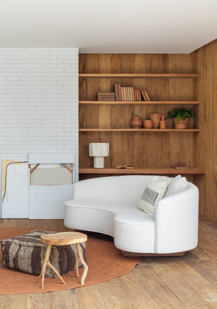 Cobertura de 200 m² ganha piscina com azulejos coloridos e área gourmet. Projeto de Escala Arquitetura. Na foto, sala de estar com sofá curvo branco, tapete em tom terroso, poltrona jangada, luminária de piso.